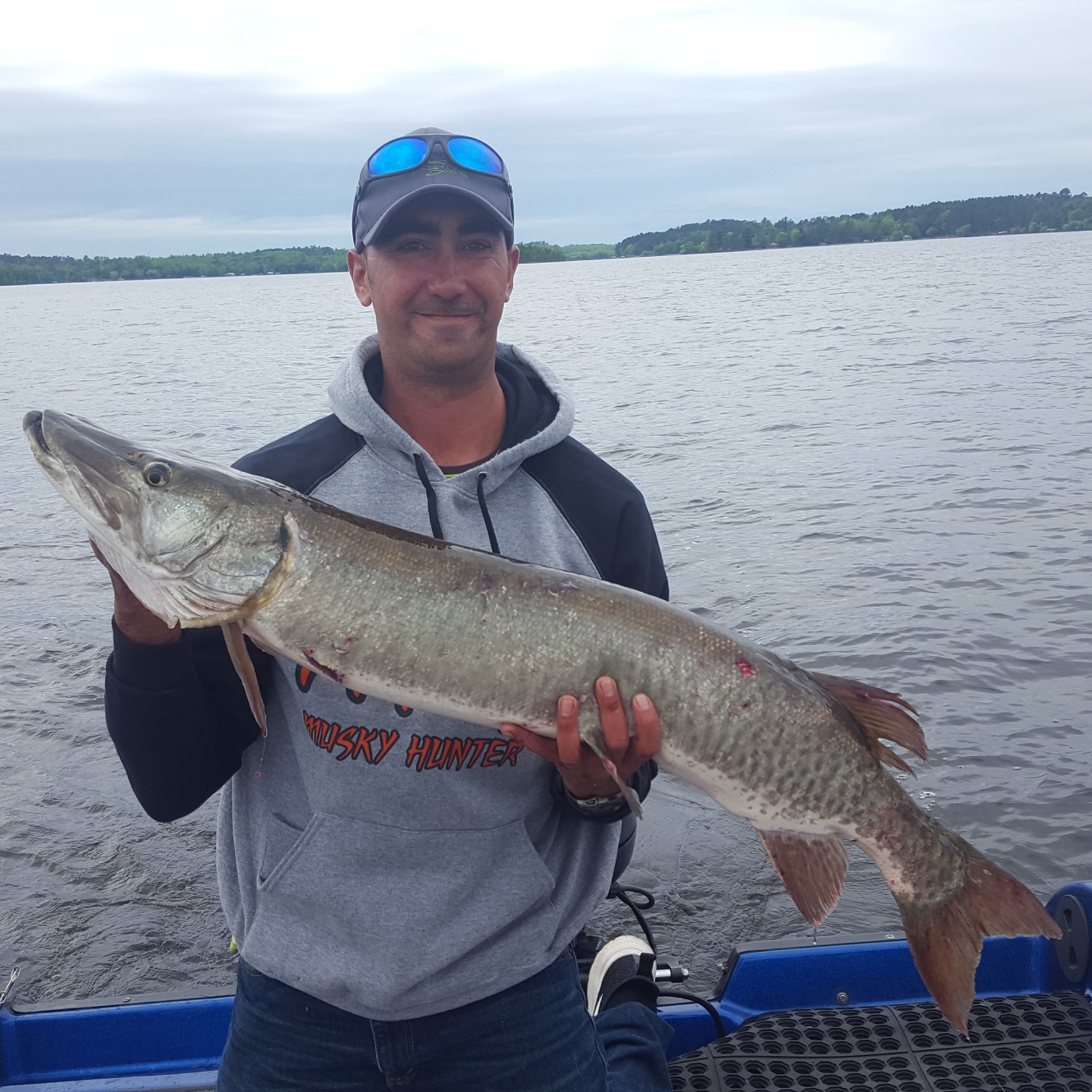 Gentleman holds a large muskie he caught on the Lake Vermilion during a cloudy day