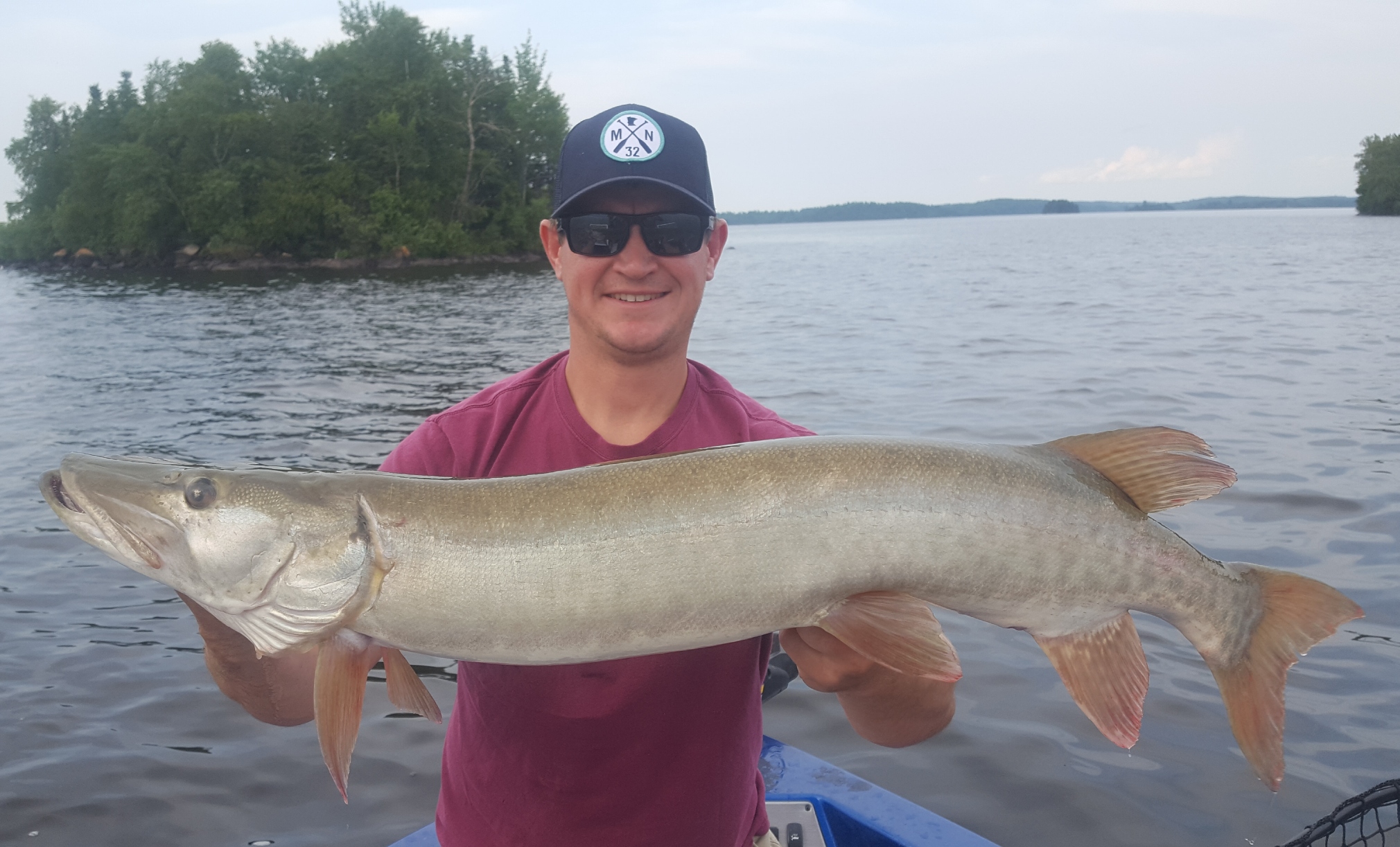 Guy holds a large fish he caught with pro muskie guides Living Legends