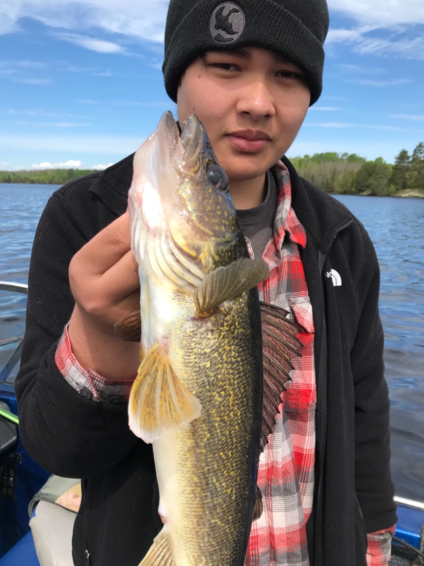 Kid holding up a walleye that he caught on a nice day