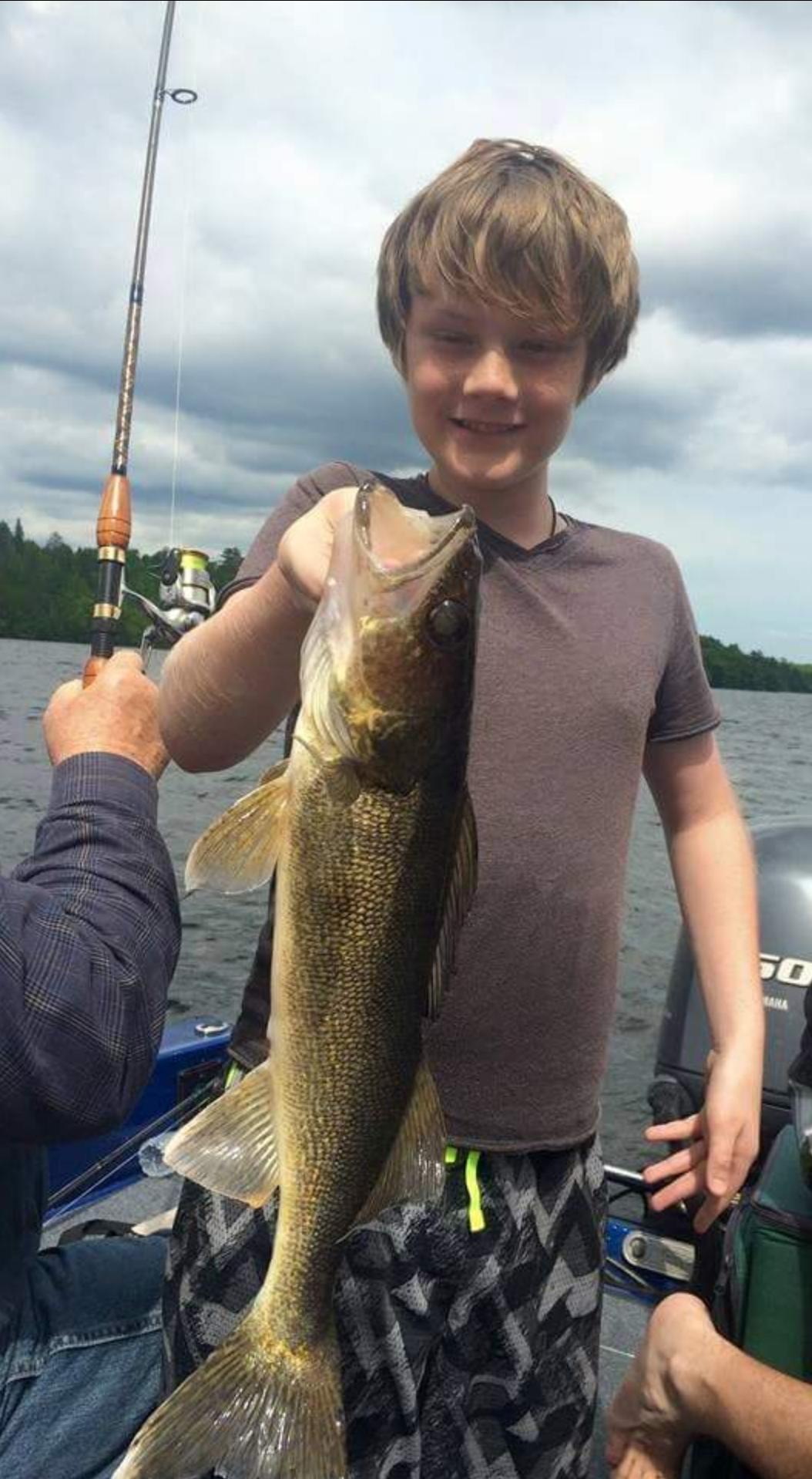 Young kid holding up a walleye that he caught