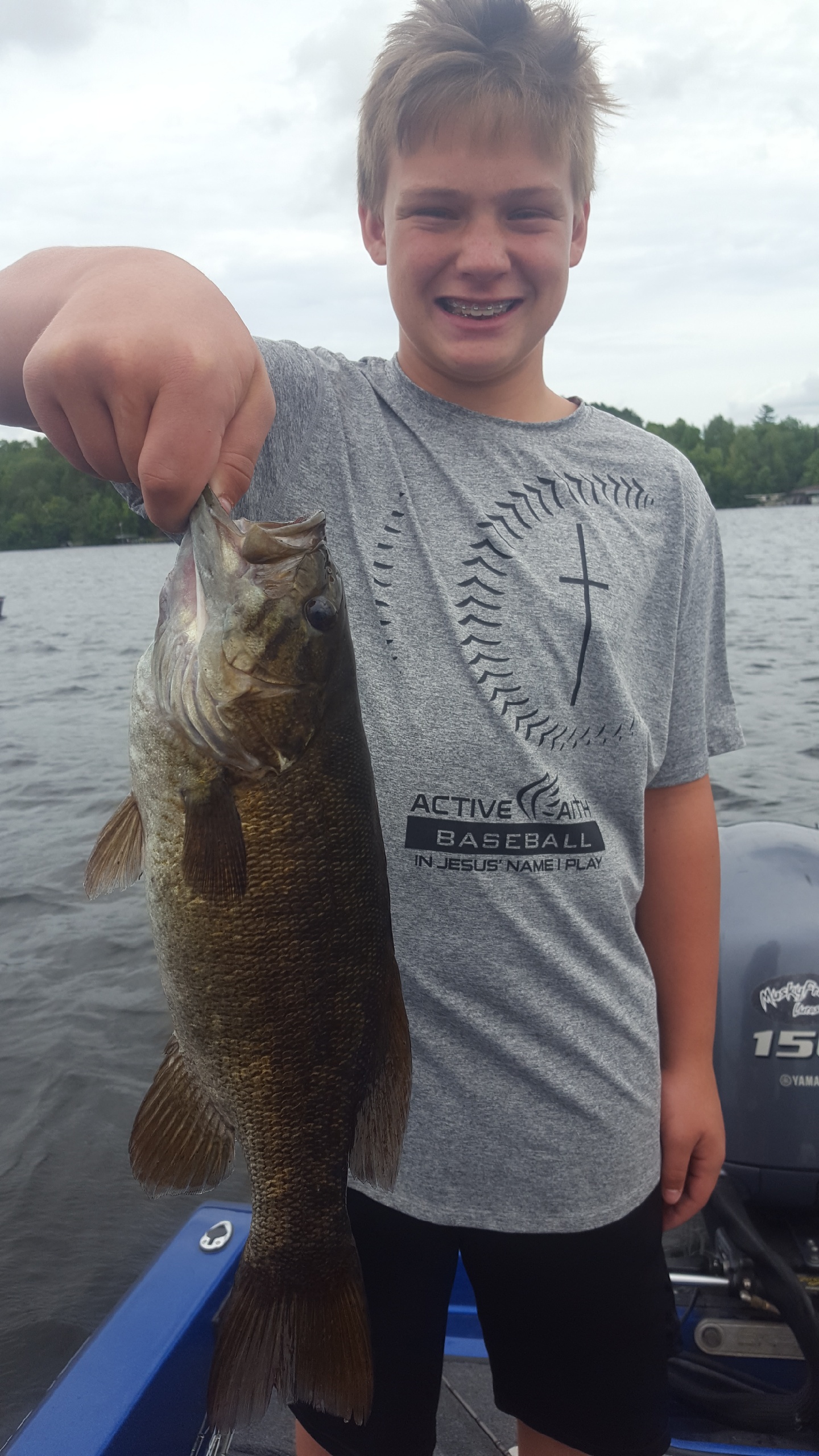Young kid holding up a walleye that he caught fishing on a cloudy day on Lake Vermilion