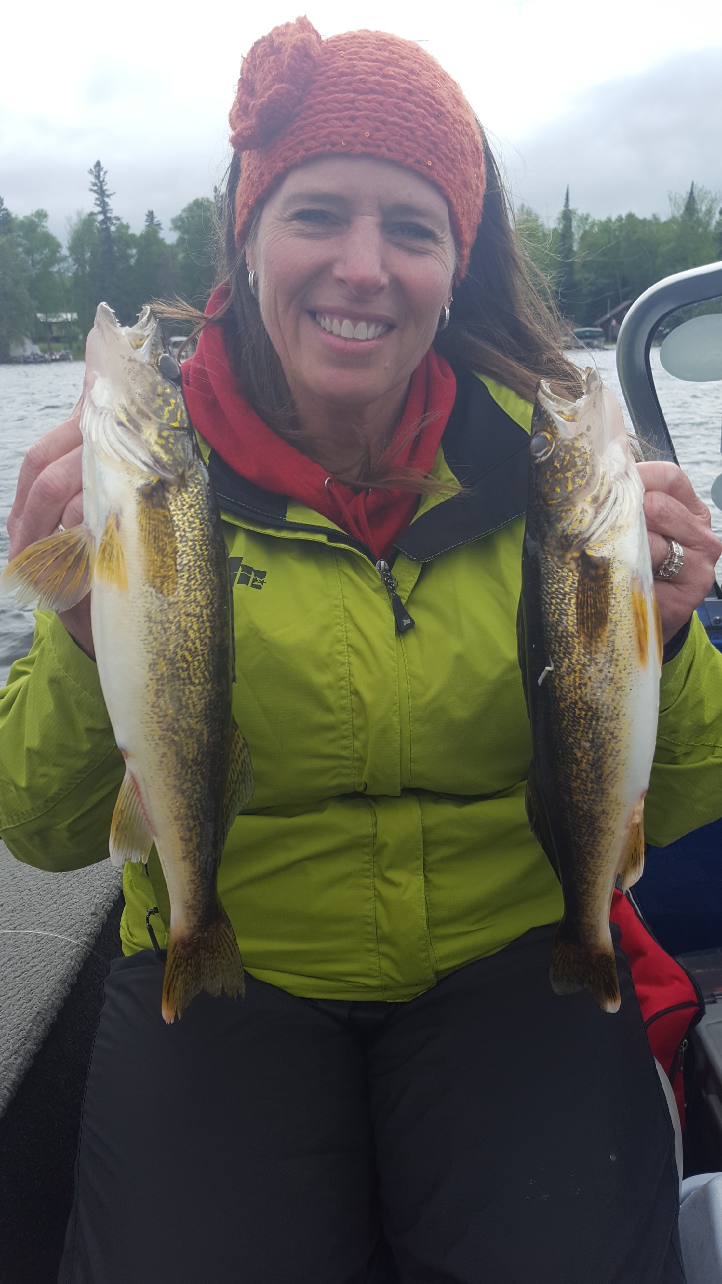 Woman smiling and holding a walleye in each hand that she caught fishing