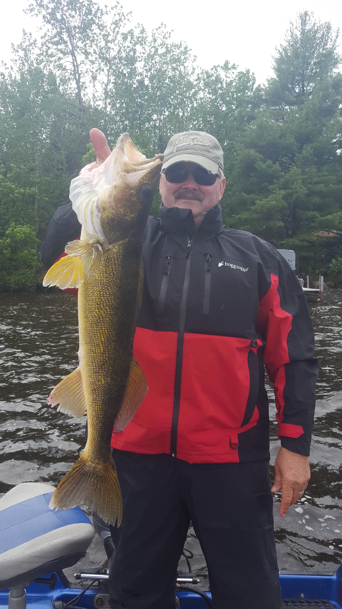 Man holding up a large walleye that he caught fishing 
